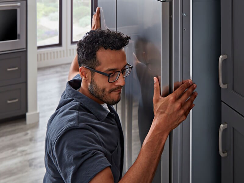A man installing a KitchenAid® refrigerator A man installing a KitchenAid® refrigerator