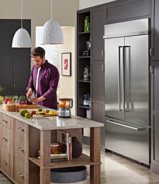 A person cooking in their kitchen with KitchenAid® appliances