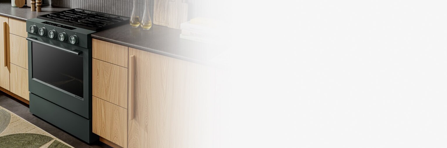 A gas range in Juniper in a kitchen with light brown cabinets