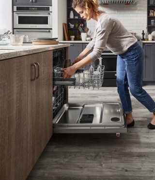 A person unloading a dishwasher in a kitchen