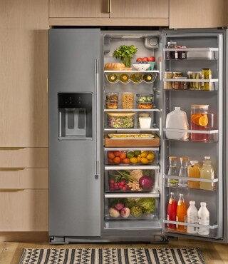 An opened refrigerator with fruits and vegetables stocked inside
