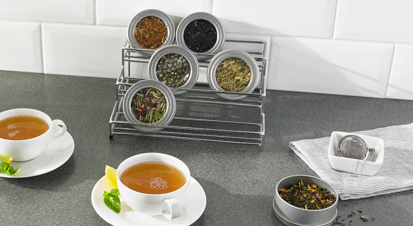 Two cups of tea and containers of loose leaf tea Two cups of tea and containers of loose leaf tea