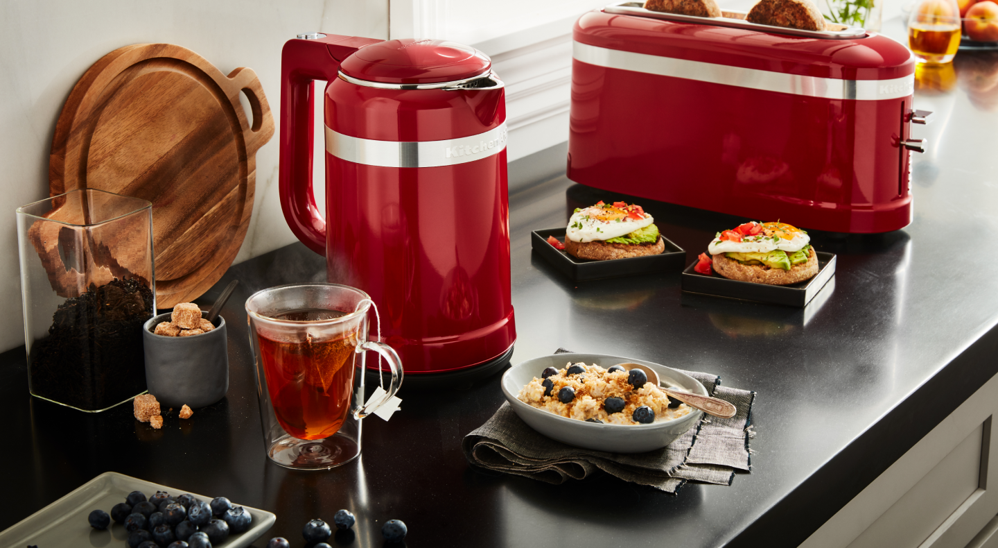 Red KitchenAid® electric kettle next to a cup of tea and breakfast bowl Red KitchenAid® electric kettle next to a cup of tea and breakfast bowl