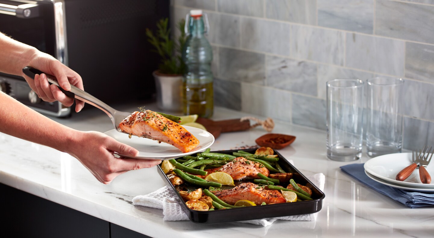 Person placing salmon filet on a plate