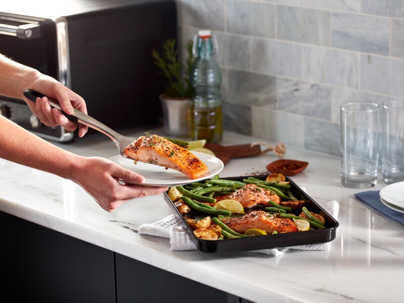 Person placing salmon filet on a plate