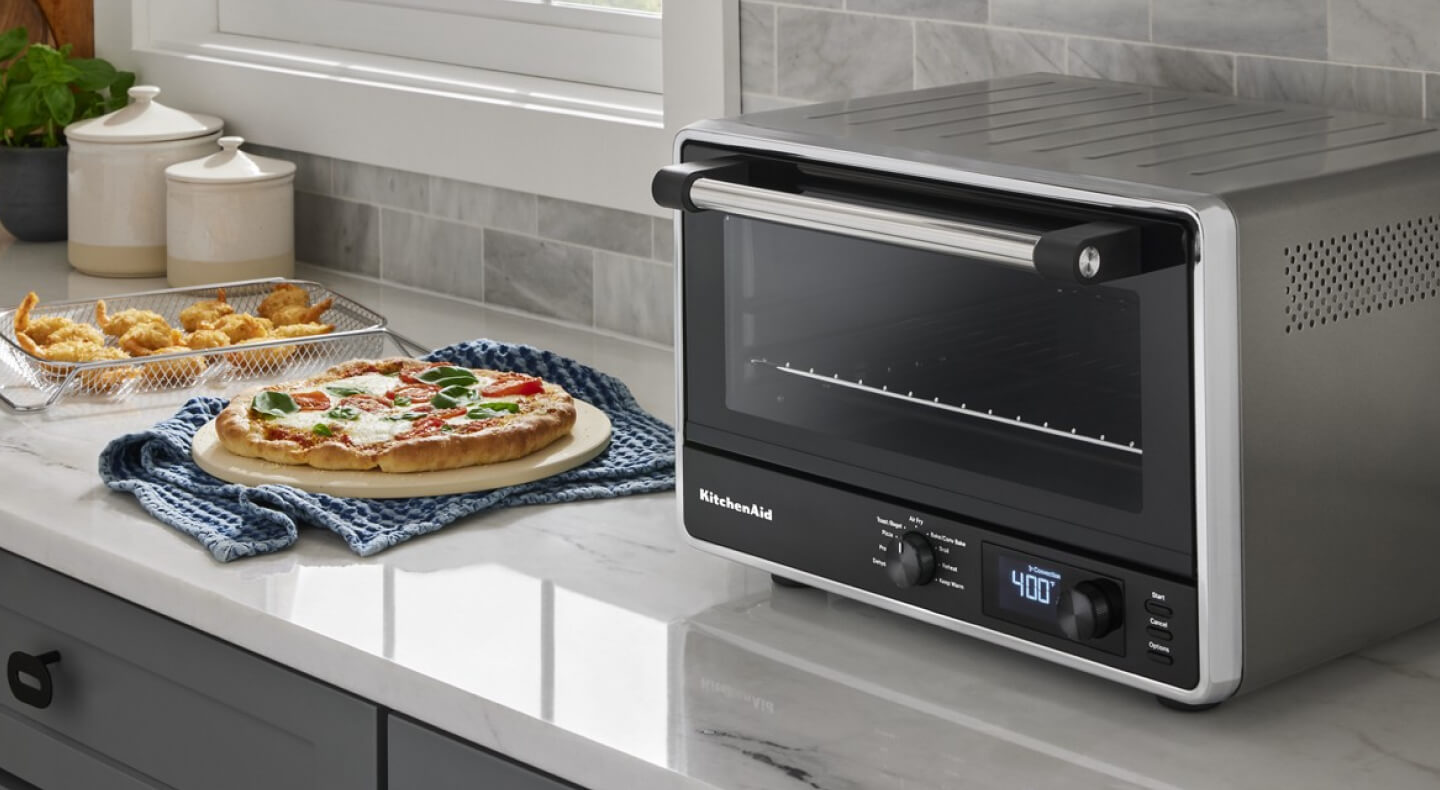 KitchenAid® digital countertop oven next to homemade pizza