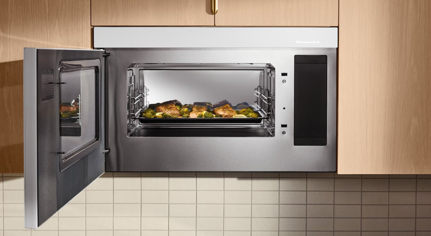 Fish and broccoli on tray inside a KitchenAid® microwave with the door open