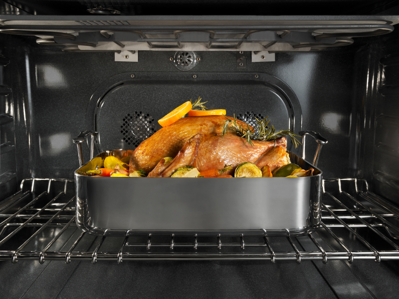 Chicken and vegetables roasting inside an oven Chicken and vegetables roasting inside an oven