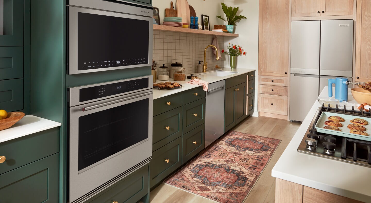 A kitchen with deep green cabinetry and stainless steel appliances