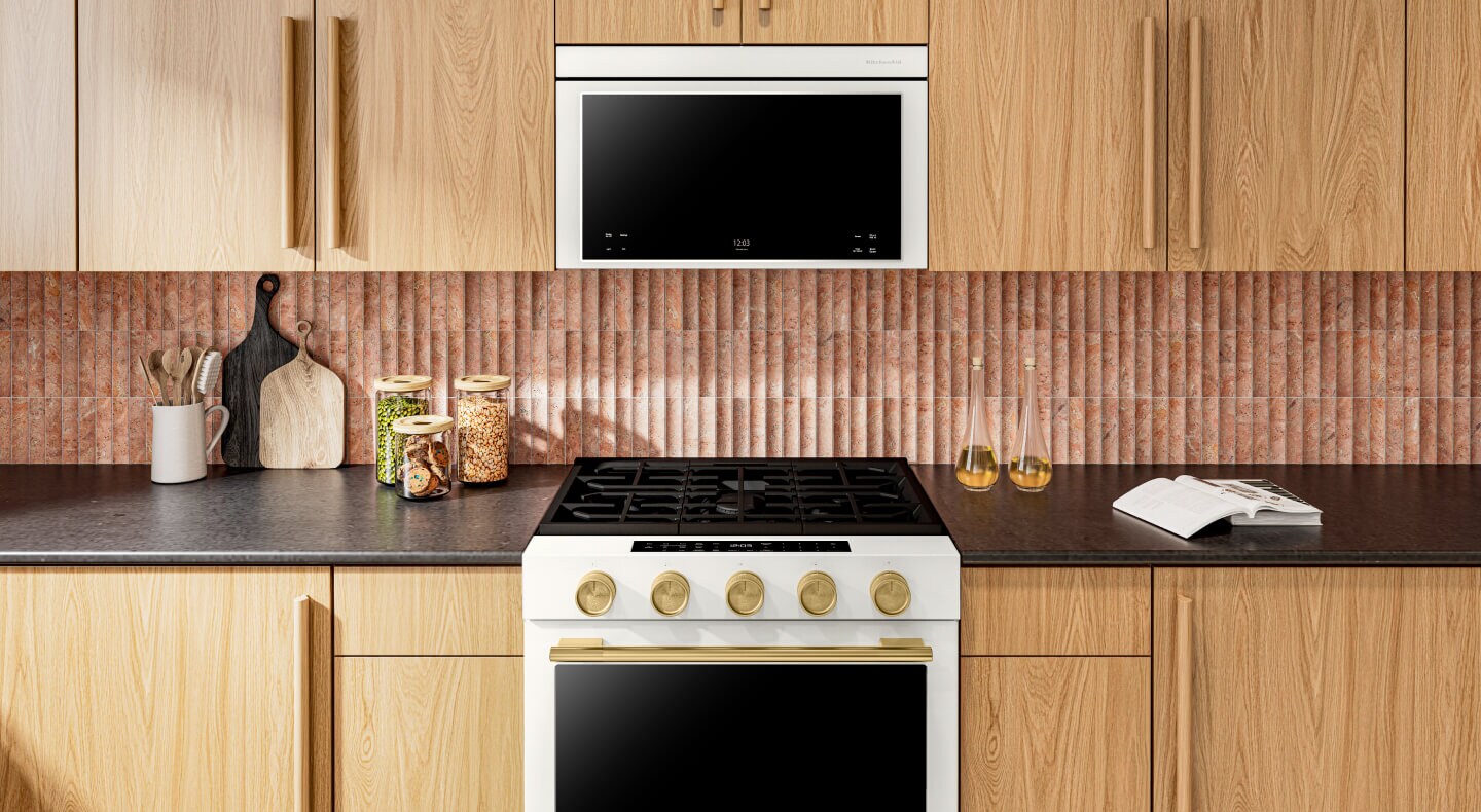 A range and over-the-range oven surrounded by light, wooden cabinetry