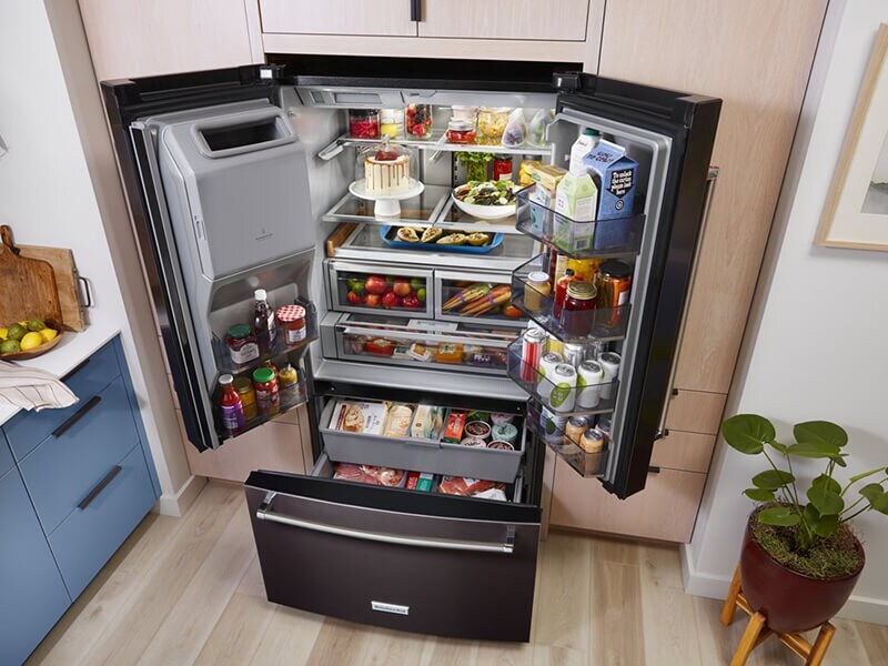 Bird’s-eye view of black stainless French door refrigerator stocked with food Bird’s-eye view of black stainless French door refrigerator stocked with food