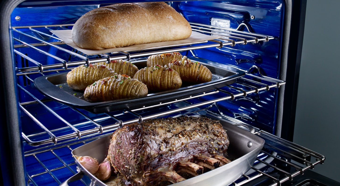 A rack with trays of meat, potatoes and a loaf of bread A rack with trays of meat, potatoes and a loaf of bread