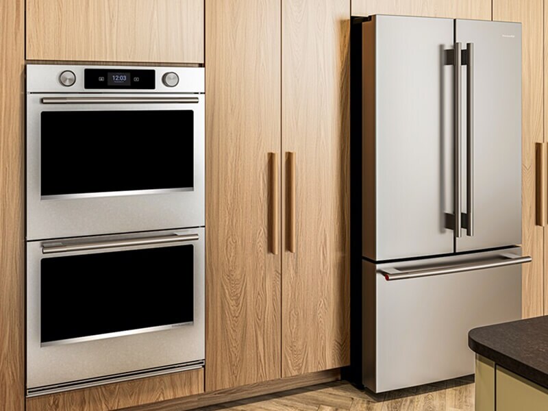 A modern minimalist wood kitchen with a double wall oven, french door refrigerator and an island
