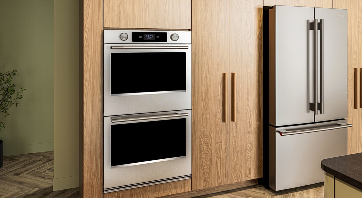 A modern minimalist wood kitchen with a double wall oven, french door refrigerator and an island