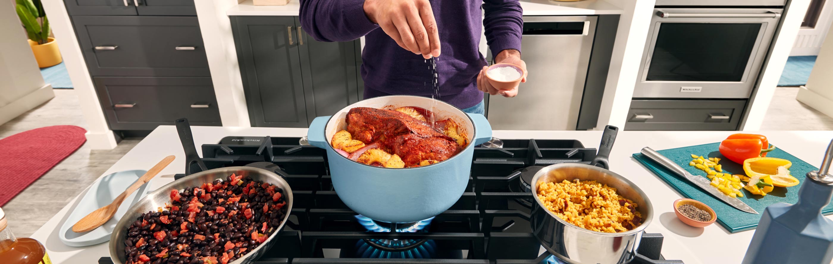A person cooking several dishes on their stovetop