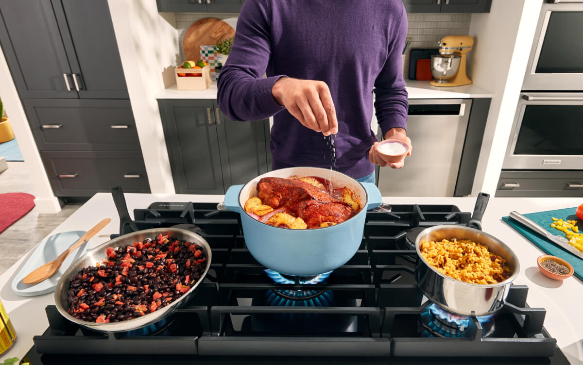 A person cooking several dishes on their stovetop