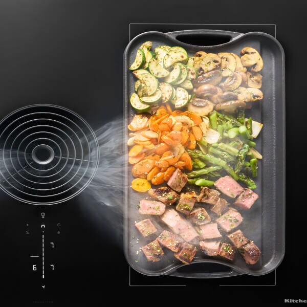 Food cooking on a griddle resting on the bridge element of an electric cooktop