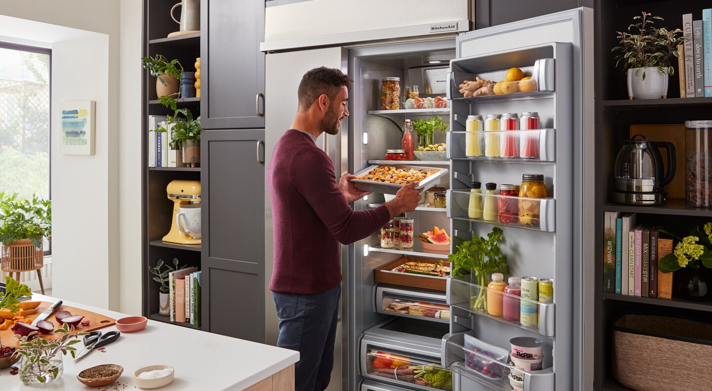 Man removing marinating drawer from refrigerator