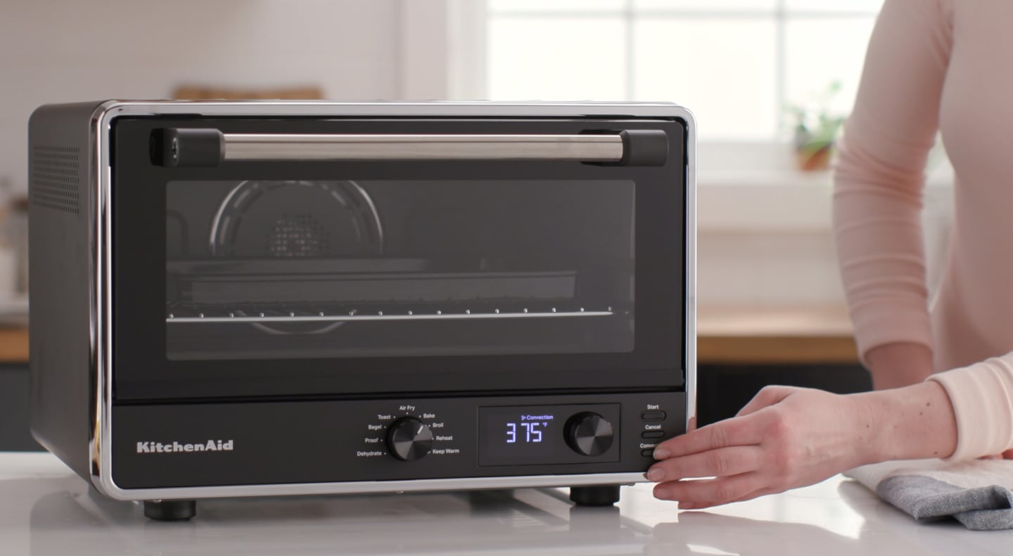 Person choosing a setting on a countertop oven Person choosing a setting on a countertop oven