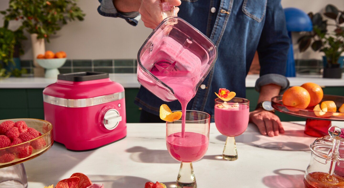 A man pouring a freshly made smoothie from a KitchenAid® blender pitcher into a glass.  A man pouring a freshly made smoothie from a KitchenAid® blender pitcher into a glass.