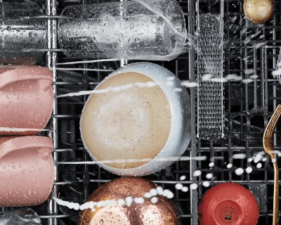 Water spraying on wet dishes loaded in a dishwasher rack
