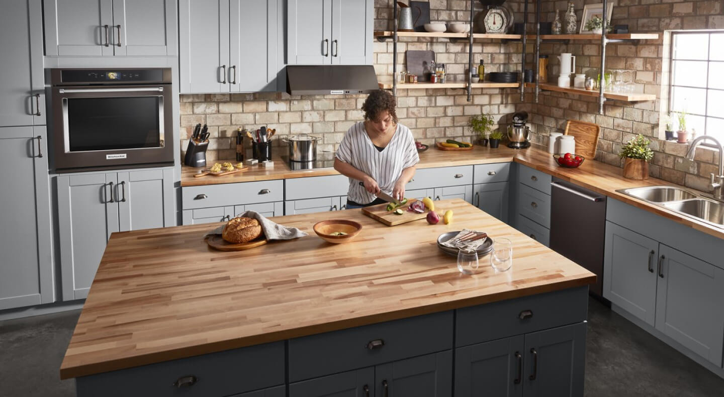 Person cutting vegetables on a kitchen island Person cutting vegetables on a kitchen island
