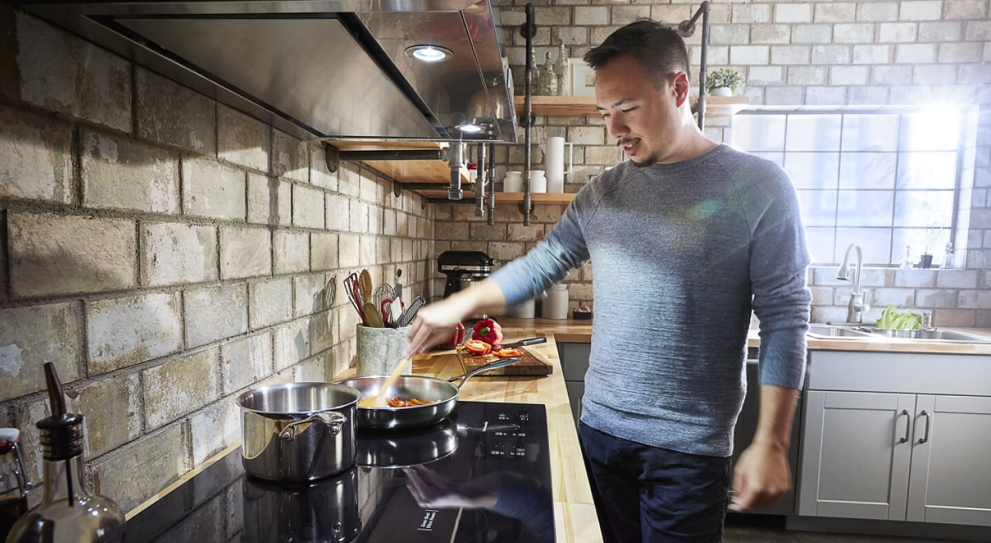 Person sautéing food on a KitchenAid® induction cooktop Person sautéing food on a KitchenAid® induction cooktop