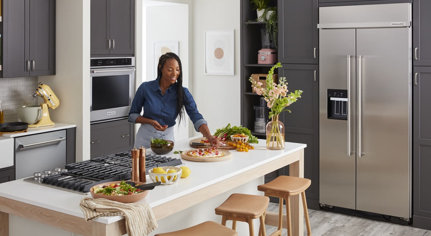 Person garnishing dishes on a kitchen island Person garnishing dishes on a kitchen island