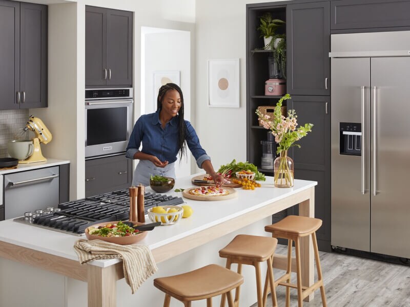 Person garnishing dishes on a kitchen island Person garnishing dishes on a kitchen island