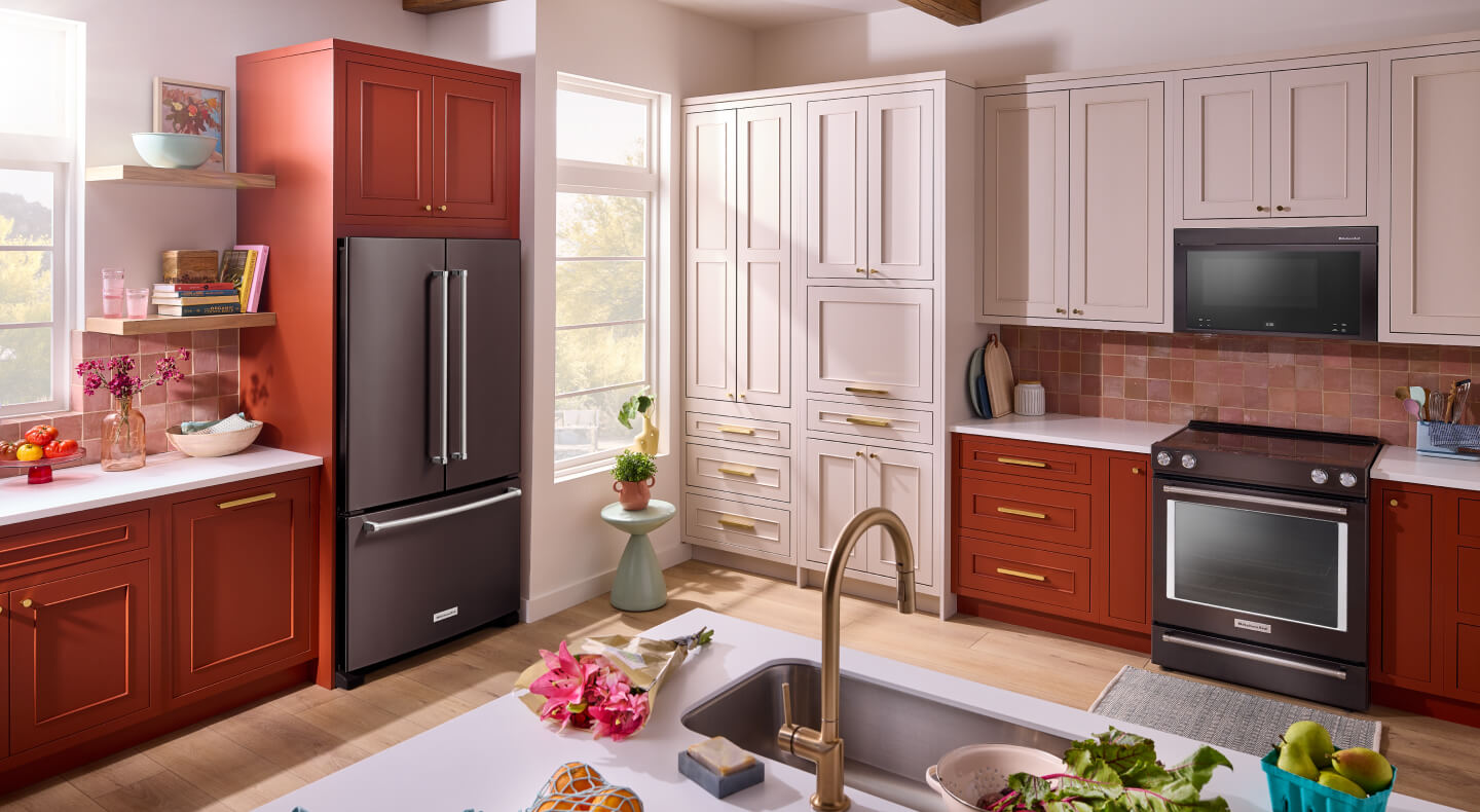 A bright kitchen with white and red cabinets and dark appliances