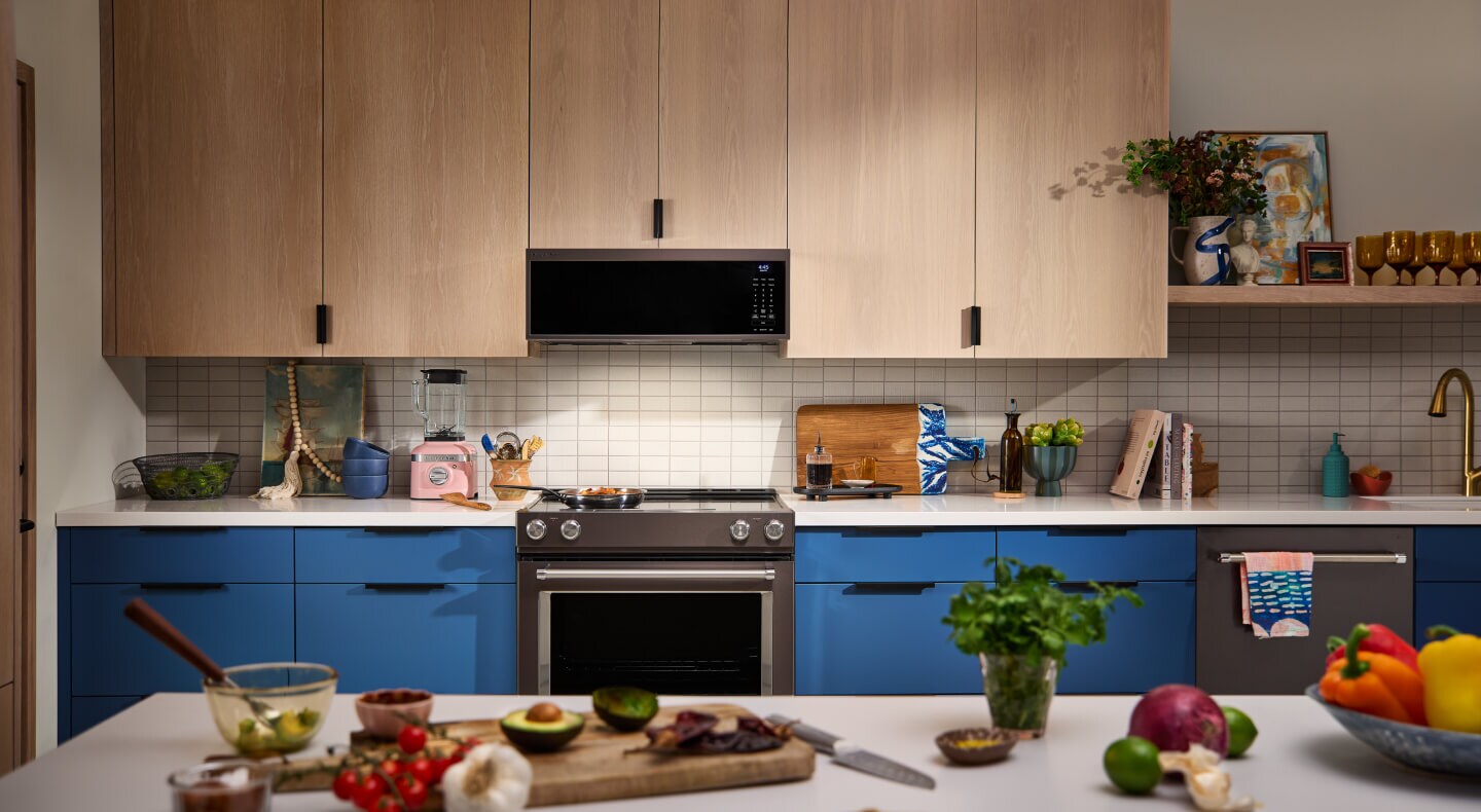 A kitchen with a range and microwave, blue cabinets and white countertops