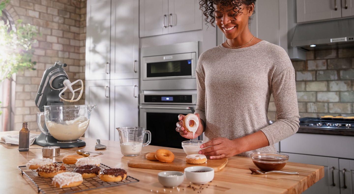 Person dipping a donut in homemade frosting Person dipping a donut in homemade frosting
