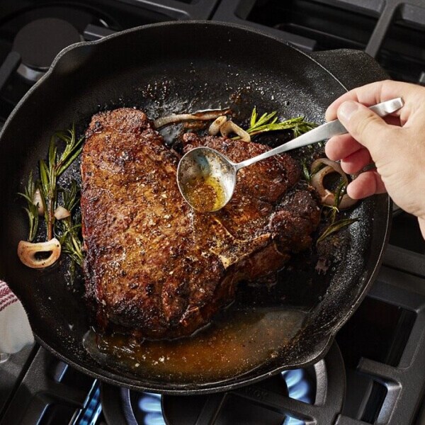 Steak being basted in a cast iron skillet