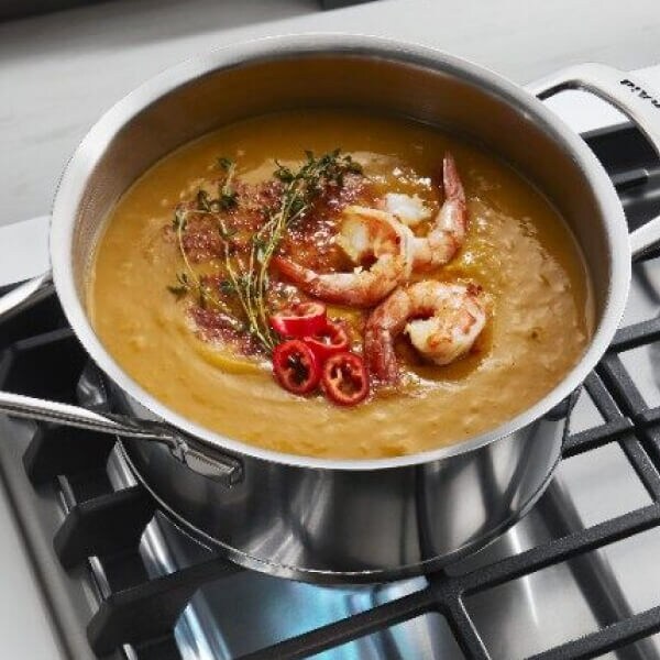 Seafood bisque simmering in a stainless steel pot on a gas stove