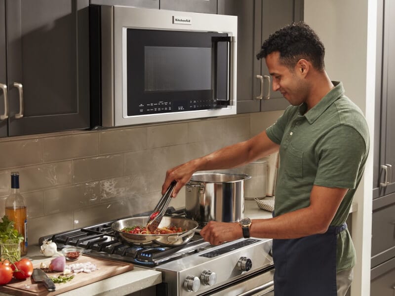 Person stirring a pasta dish on a KitchenAid® stovetop