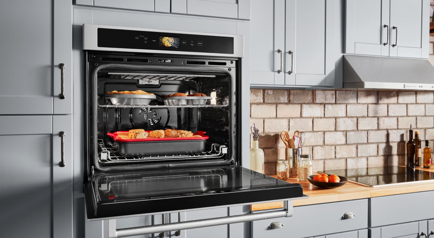 Open, single wall oven with food cooking on the top and bottom racks Open, single wall oven with food cooking on the top and bottom racks