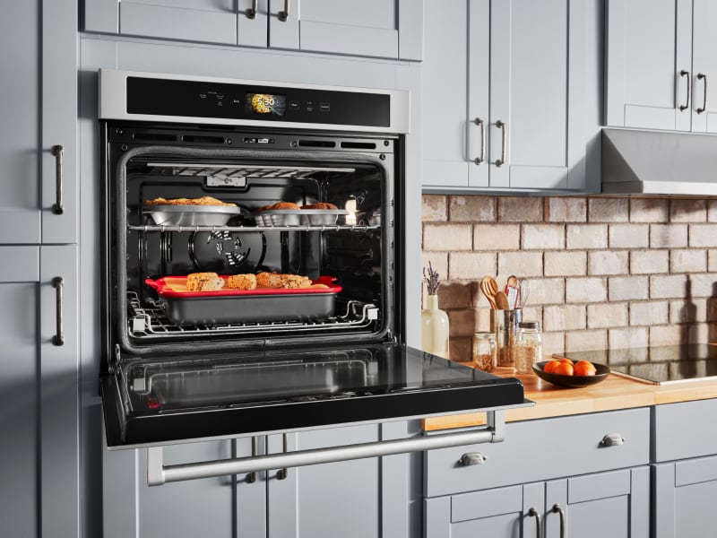 Open, single wall oven with food cooking on the top and bottom racks Open, single wall oven with food cooking on the top and bottom racks
