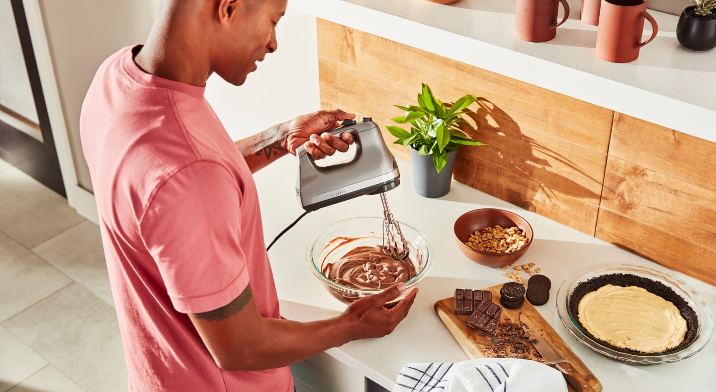 Person using hand mixer with Flex Edge Beaters Person using hand mixer with Flex Edge Beaters