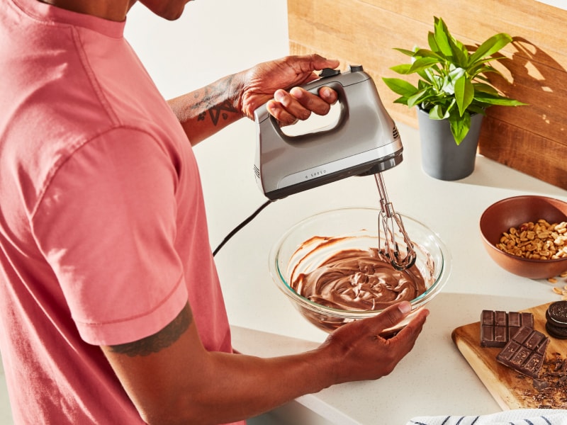 Person using hand mixer with Flex Edge Beaters Person using hand mixer with Flex Edge Beaters