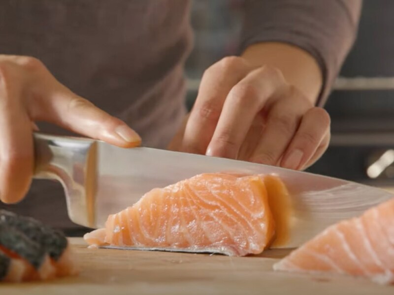  A man cutting fresh, raw salmon on a cutting board. 
