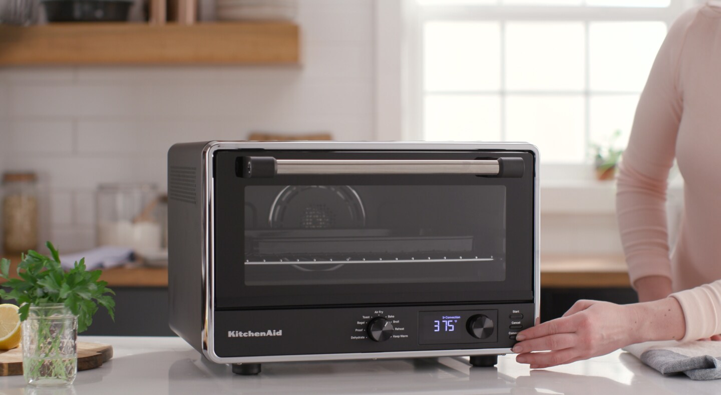 Person pressing setting on KitchenAid® countertop oven Person pressing setting on KitchenAid® countertop oven