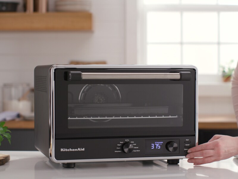Person pressing setting on KitchenAid® countertop oven Person pressing setting on KitchenAid® countertop oven