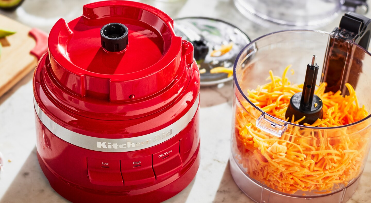 Red KitchenAid® food processor with shredded cheese in it Red KitchenAid® food processor with shredded cheese in it