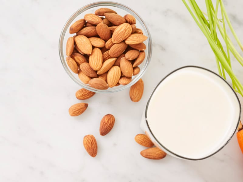 A bowl of almonds and a glass of almond milk A bowl of almonds and a glass of almond milk