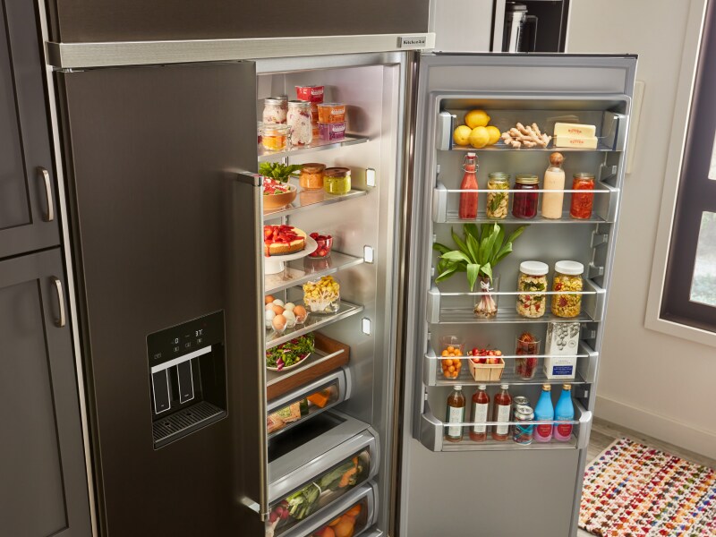 An open refrigerator door where food items are being stored An open refrigerator door where food items are being stored