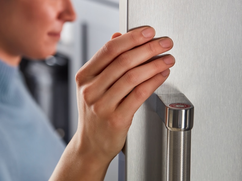 A closeup of a person looking inside a KitchenAid® refrigerator.
