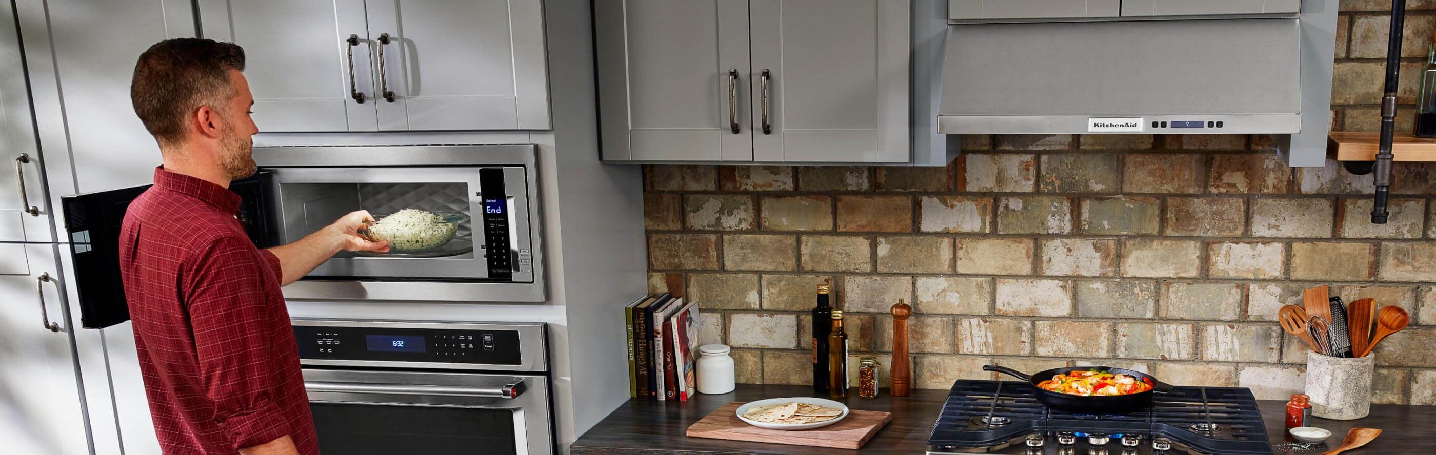 Man removing a bowl of popcorn from the microwave oven in his kitchen