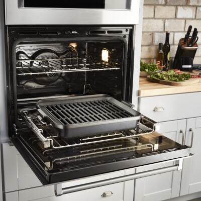An open KitchenAid® oven with a grill pan
