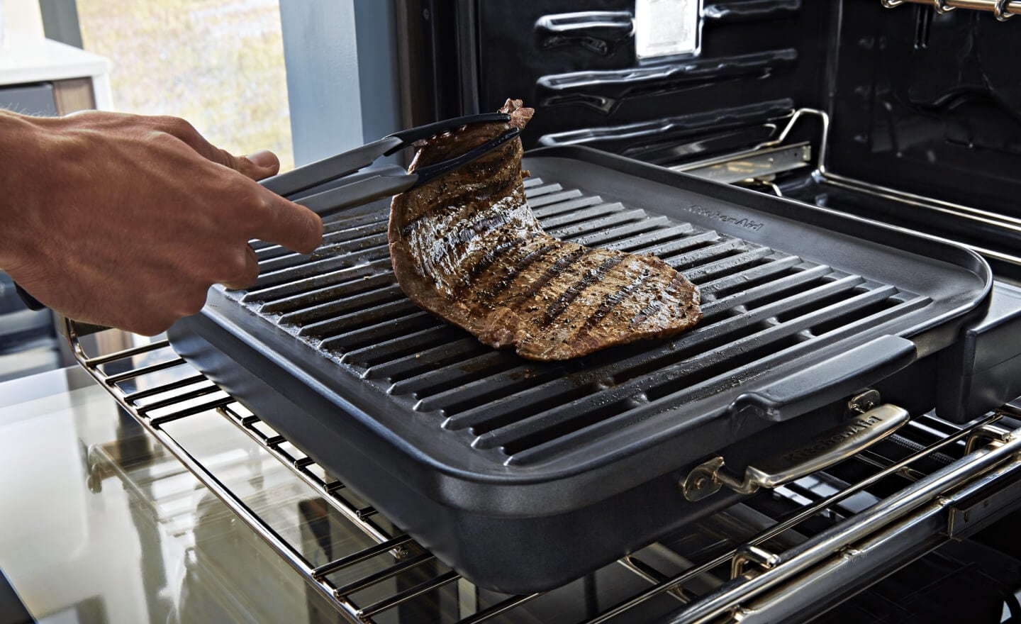 A person grilling a steak in an oven