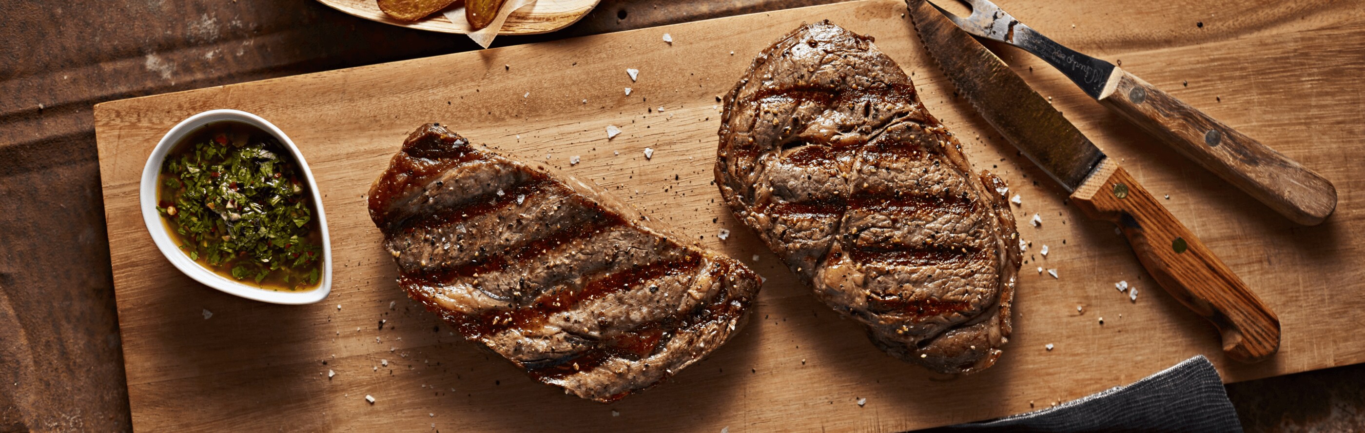 Two grilled steaks on a cutting board